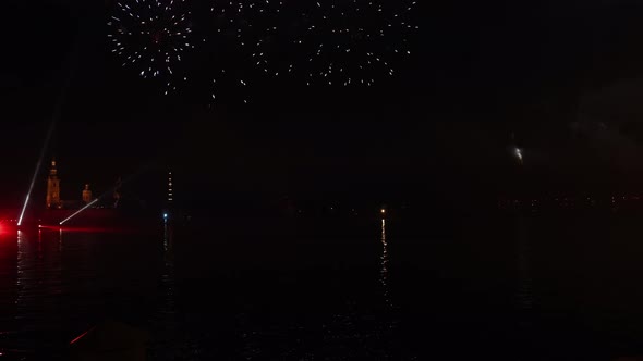 Festive colorful fireworks and illumination in dark sky with beautiful reflection in water.