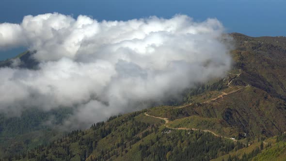Road From the Forest and Bushes on the Mountain Ridge Above the Clouds alt