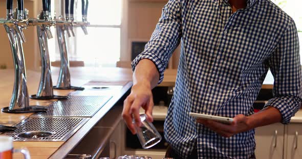 Bar tender using digital tablet at counter 4k alt