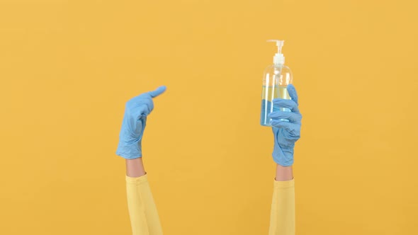 Hands wearing rubber gloves recommend using and pointing to alcohol gel sanitizer