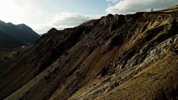 Hilly Mountains Against a Background of Blue Sky and Gray Clouds Illuminated By the Sun alt
