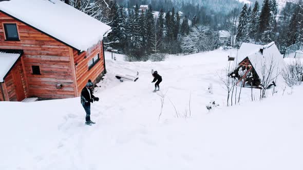 Happy Couple Enjoying Snowfall and Playing with the Snow Outside the Wooden House alt