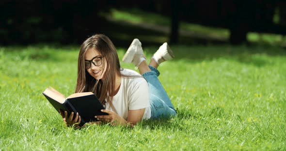 Woman Reading Book Lying on Grass