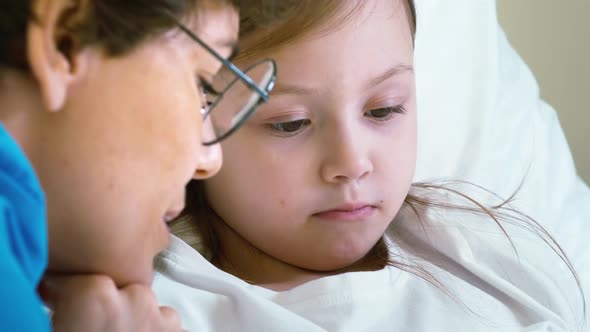 Woman encouraging girl in hospital room