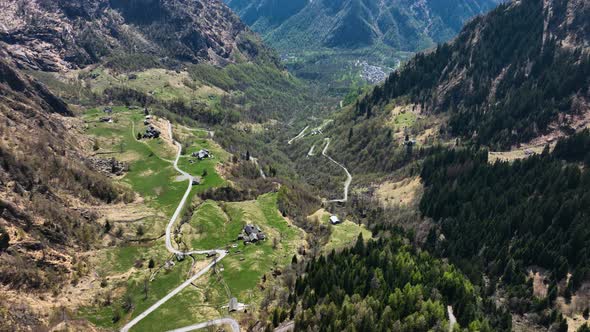 Twisted road through small secluded village in Italian alp valley - drone alt
