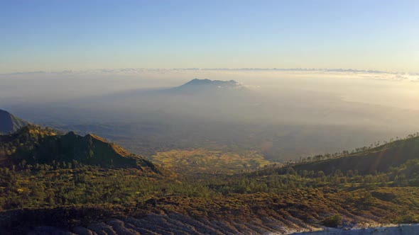 Aerial view of rock cliff at Kawah Ijen volcano with forest and fog  at East Java, Indonesia. alt