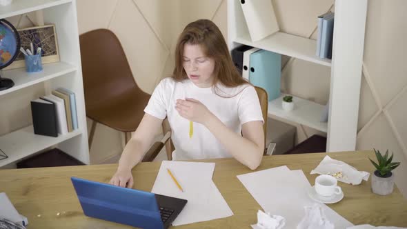 Top View of Young Woman Sending Project Online and Lying Head Down on the Table alt