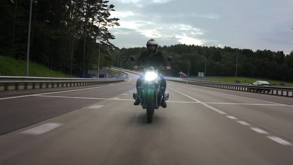 Man Riding Scrambler Motorbike on the Highway Through the Forest Front View alt