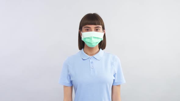 Lovely Young Girl in Blue Shirt Wearing Respiratory Mask and Looking To the Camera alt