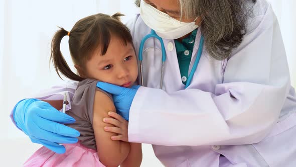 Doctor holding syringe for prepare vaccinated in the shoulder of Asian girl kids in the hospital. Pe alt