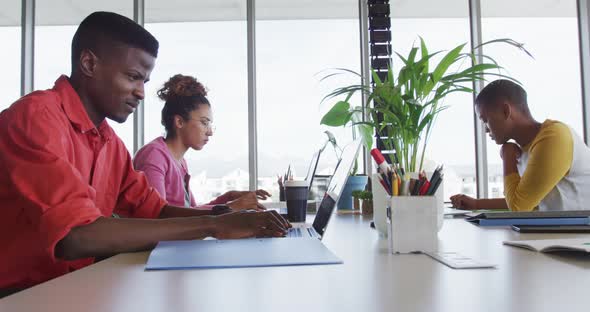 African american creative businessman celebrating in office, with diverse female colleagues working alt