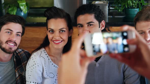 Woman clicking photo of friends on mobile phone alt