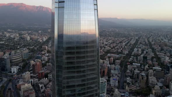 Aerial orbit of curtain wall Costanera Center skyscraper, Mapocho river, hills in background at blue alt