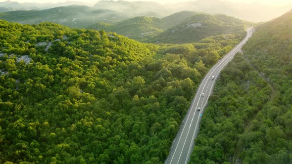 Amazing sunset aerial top drone view of high-speed road between the picturesque mountains.