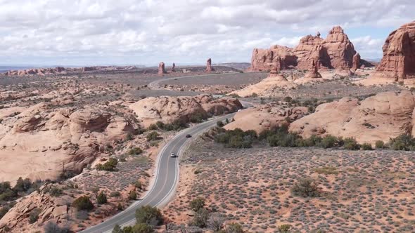 Cars driving down a long desert road. alt