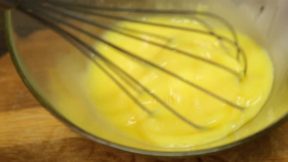 Person preparing homemade omelette mixing with whisk eggs. Close up. 4k