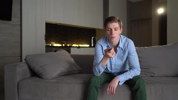 Caucasian Young Man Tries to Watch the Game on TV While His Girlfriend Distracts Him with Kisses and alt