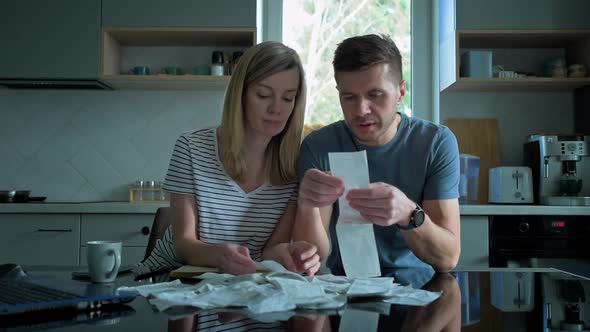 Man and Woman Looking at Payment Bills in the Kitchen alt