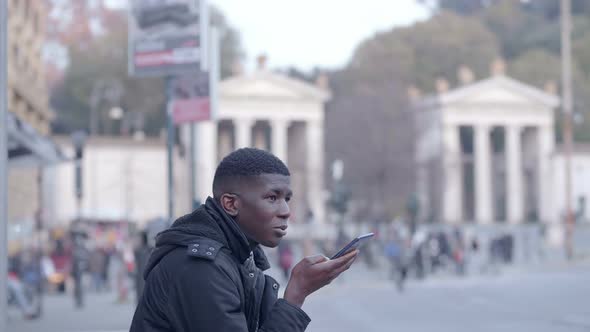 young black african man talking free-hands at mobile in the city alt