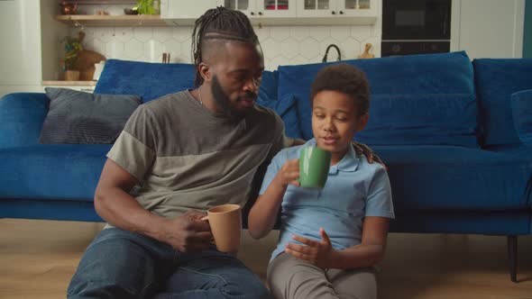 Positive African Father and Adorable Son Resting and Bonding in Domestic Room alt