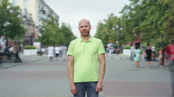 Zoomout Time Lapse of Pensive Man Standing in Street Downtown and Looking at Camera alt