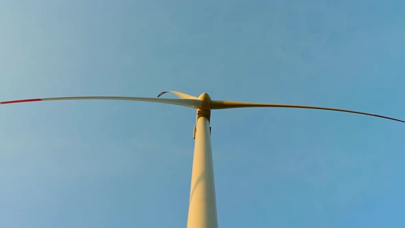 Wind turbine in an offshore wind farm in the green field against low sun on sun