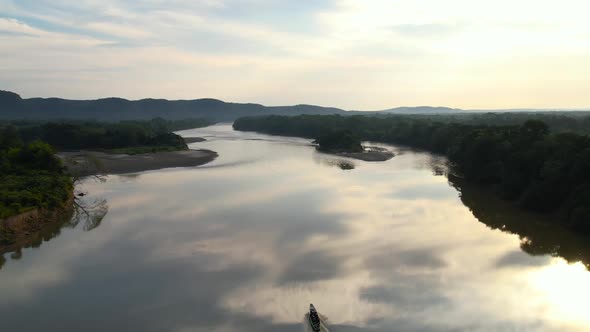 A small boat going up a tranquil river in the Amazon on a perfectly calm afternoon alt