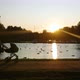 woman walks with a stroller by the lake in the sunset - VideoHive Item for Sale