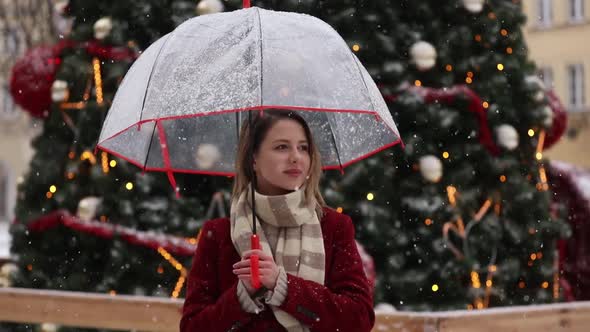 adult girl in red coat and scarf with umbrella white snowfall