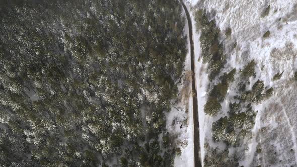 Aerial view looking down at road cutting through winter landscape alt