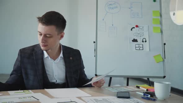 American Man Designer Working with New Blueprint at Workspace in Office Room.
