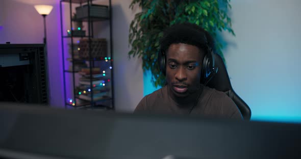 A Player is Playing on a Computer with His Team with Whom He is Talking Through a Headset a Man alt