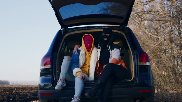 Women in Balaclavas Chill Sitting in the Trunk of a Car