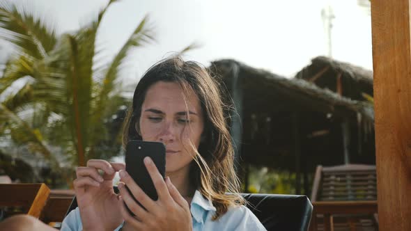Happy Confident Businesswoman Sitting in Beach Lounge Chair Using Smartphone Mobile Office App on alt