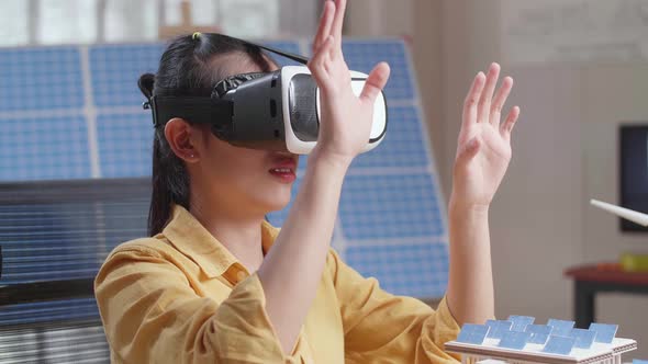 Woman Working With A Model Of Small House Roof Solar Panel Wearing Vr And Showing Touching Gesture alt