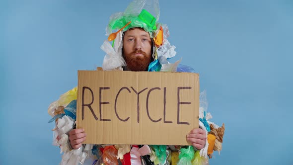 Man dressed in junk costume holding plate with inscription recycle