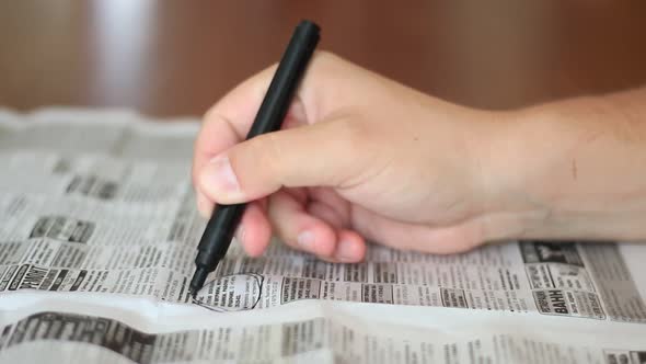 Man Highlighting The Advertisements In Newspaper With Marker