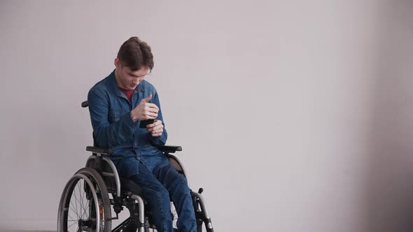 Young Man in Wheelchair Using His Smartphone at Home