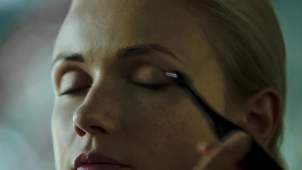 Makeup artist applying eye shadow on womens eyes