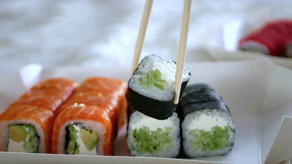 Wooden Sticks Take the Maki Roll and Dip It Into the Soy Sauce