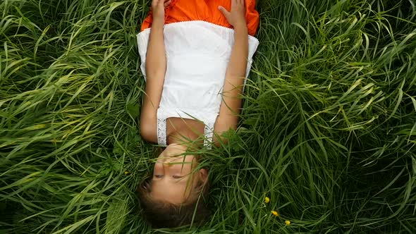 Little Girl Resting on the Green Grass. Beautiful Kid Lying on the Field