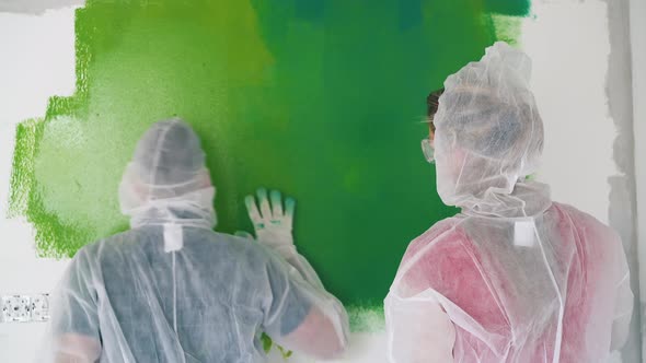 Woman Paints Room Wall Near Dancing Man in Coverall at Home alt