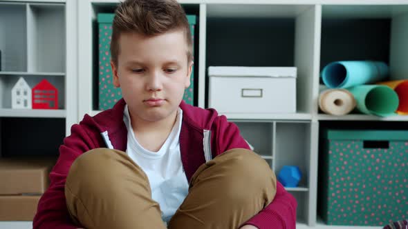 Portrait of Sad Kid Sitting on Floor at Home Sighing Feeling Bored and Unhappy alt