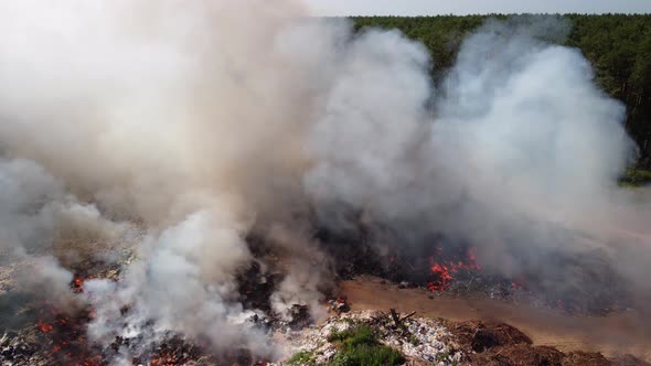 Clouds of smoke exhaling from burning trash at garbage dump