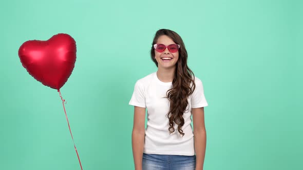 Happy Teen Girl Portrait in Sunglasses Laughing and Having Fun with Heart Party Balloon Party