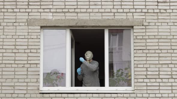 Old Man in Gas Mask Dance at Window Isolated at Home on Quarantine. Coronavirus alt