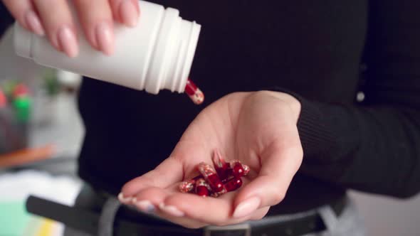 Close Up of Woman Pouring Capsules From Meds Bottle on Hand