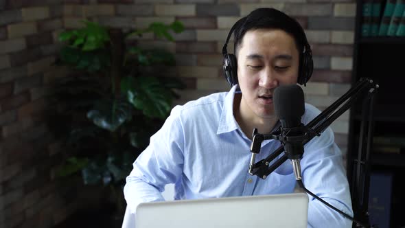 Young Adult Businessman Recording Podcast Talk Show at Home Studio with Computer Laptop on Table alt