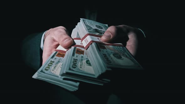 Three Stacks of 10000 American Dollars Bundles in Male Hands on Black Background alt