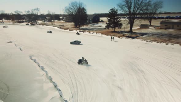atv drifting on ice lake next to other sports cars drifting along alt